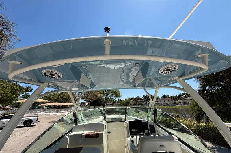 Slide: The Image of 2021 Cobia 280 Dual Console boat with blue hardtop and speakers, parked near water. - 16