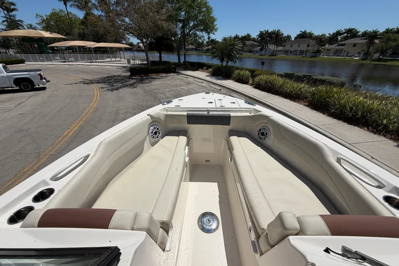 Slide: The Image of 2021 Cobia 280 Dual Console boat interior with seating, parked near a waterfront. - 8