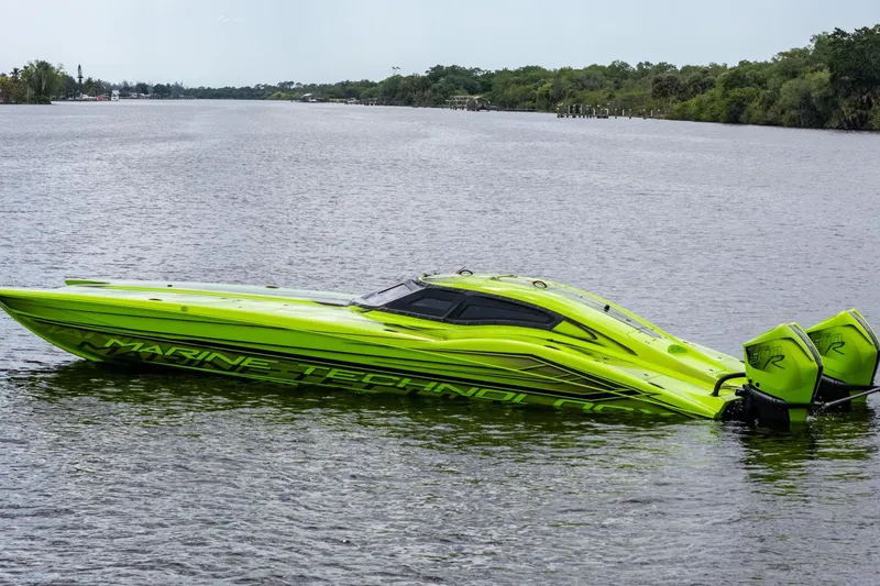 Slide: The Image of Bright green 2023 MTI 390XR speedboat on a calm river, showcasing sleek design and powerful engines. - 11