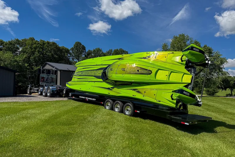 Slide: The Image of Green MTI 390XR powerboat on trailer, 2023 model, parked on lush grass under blue sky. - 3