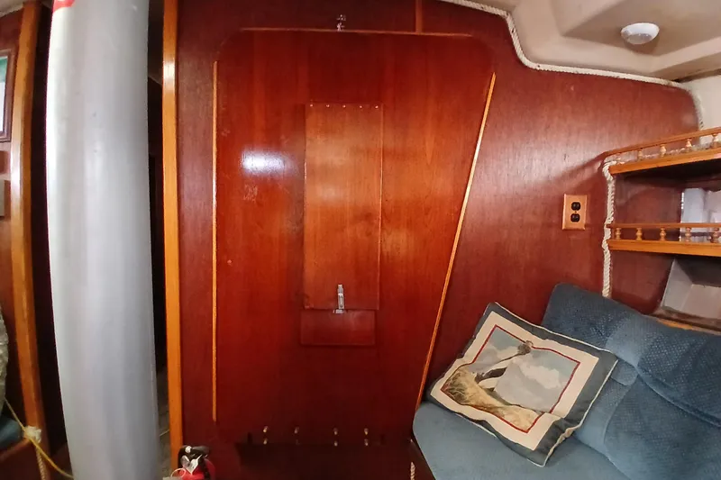 Slide: The Image of Interior of a 1982 Morgan 416 sailboat with wooden paneling and blue seating. - 12