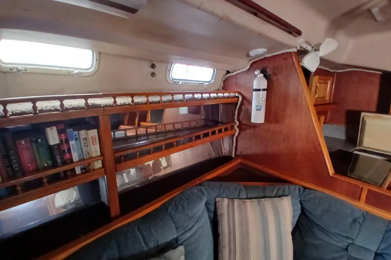 Slide: The Image of Interior of 1982 Morgan 416 sailboat with bookshelf, fire extinguisher, and cushioned seating. - 13