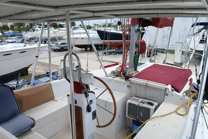 Slide: The Image of 1982 Morgan 416 sailboat cockpit with steering wheel, docked among other boats. - 7