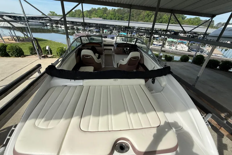 The Image of 2011 Cobalt 232 boat with white seating, docked at a marina under a covered area. - 1