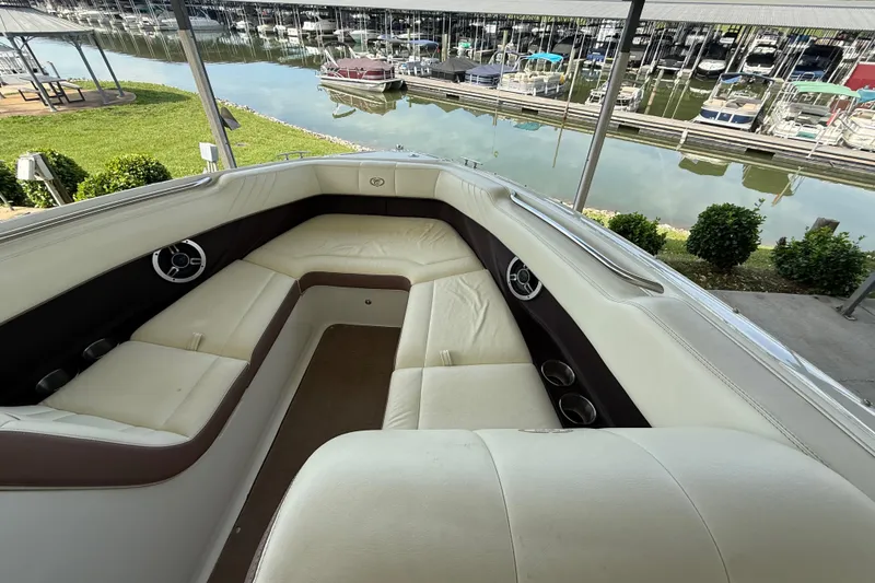 Slide: The Image of 2011 Cobalt 232 boat interior with white seating, docked near a marina. - 10