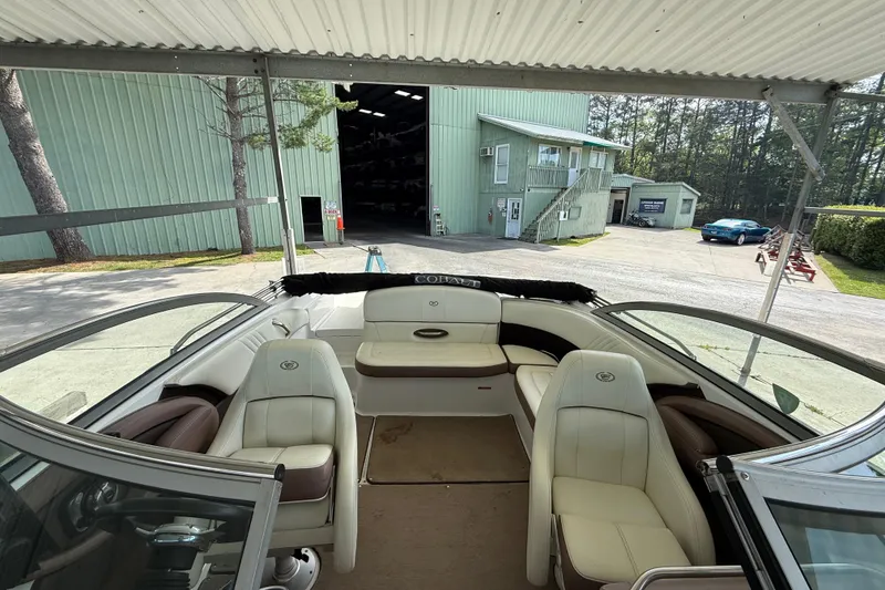 Slide: The Image of Interior view of a 2011 Cobalt 232 boat with white seating, parked near green buildings. - 11