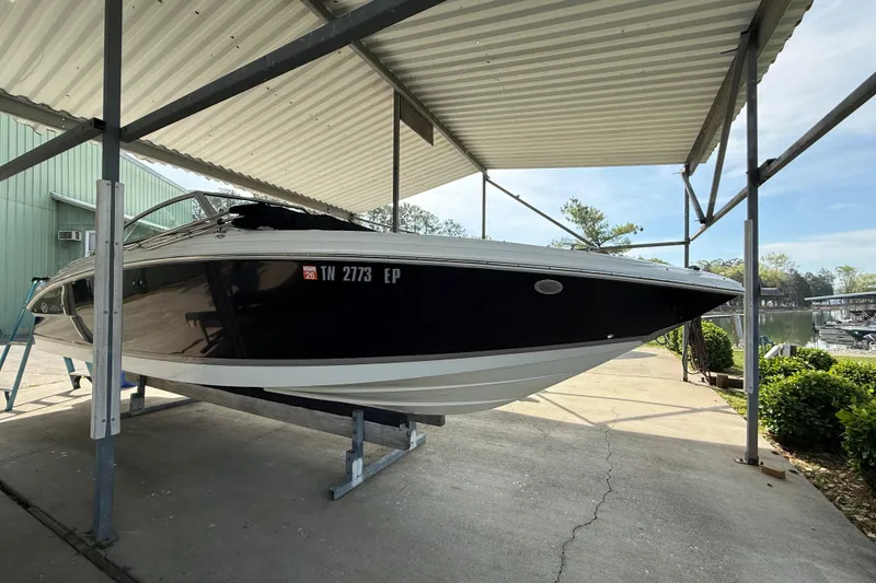 Slide: The Image of 2011 Cobalt 232 boat under a metal canopy, docked on a sunny day. - 14