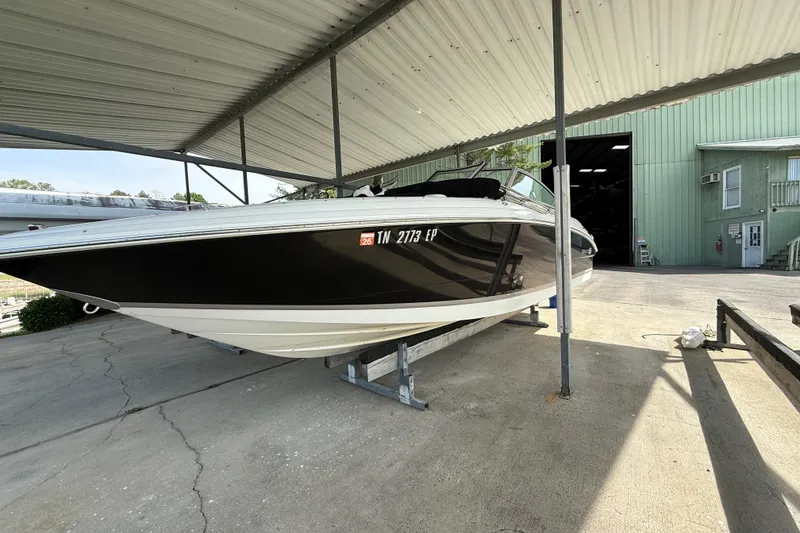 Slide: The Image of 2011 Cobalt 232 boat under a metal canopy, parked on a concrete surface. - 15