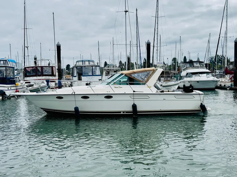 Slide: The Image of 1988 Tiara Yachts 3100 Open boat docked in a marina with sailboats. - 1