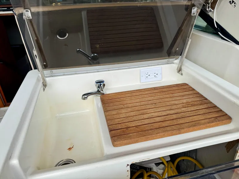 Slide: The Image of 1988 Tiara Yachts 3100 Open dashboard with navigation equipment and controls in a marina setting. - 14