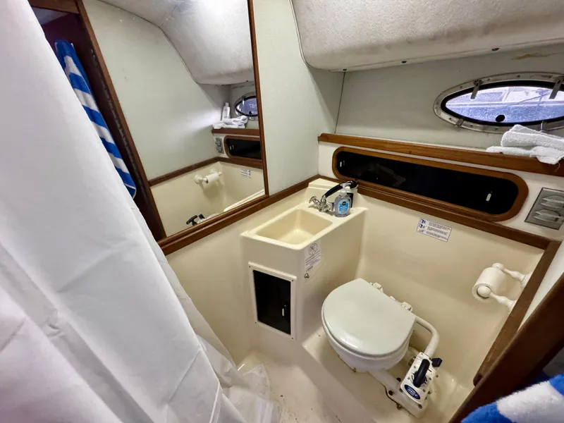 Slide: The Image of 1988 Tiara Yachts 3100 Open cabin interior with wooden cabinets and patterned bedding. - 22