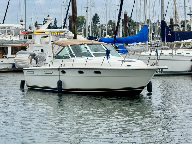 Slide: The Image of 1988 Tiara Yachts 3100 Open in marina, surrounded by sailboats and calm water. - 44