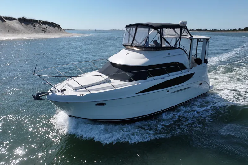 Slide: The Image of 2005 Meridian 368 Motoryacht cruising on open water near sandy shoreline. - 12