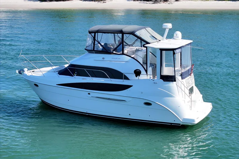 Slide: The Image of 2005 Meridian 368 Motoryacht cruising on clear blue water near a sandy shore. - 4