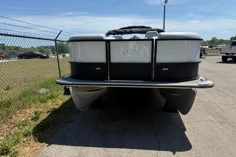 Slide: The Image of 2023 Bentley Pontoons 220 SWINGBACK pontoon boat parked on pavement near a chain-link fence. - 2