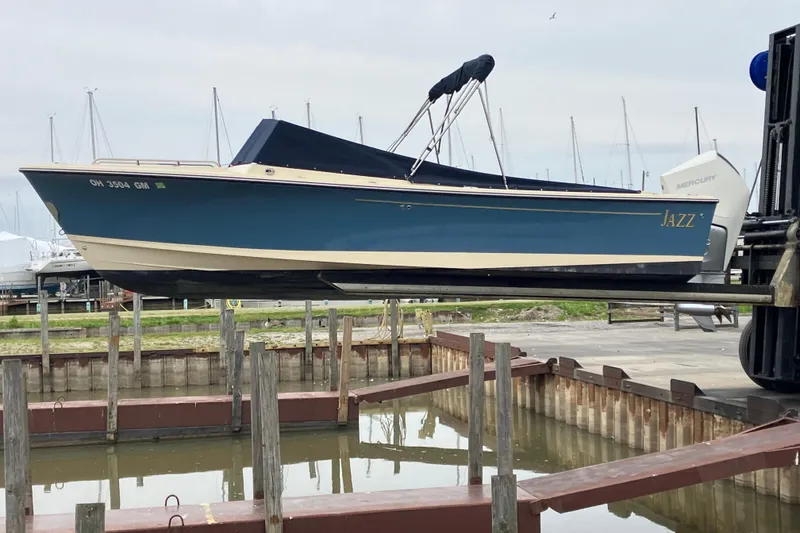 Slide: The Image of 2018 Rossiter 23 Classic Day Boat "Jazz" lifted at marina, blue hull, covered cockpit. - 1