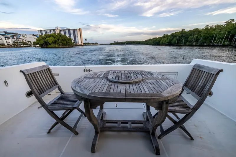 Slide: The Image of Deck view from 2003 Navigator Rival 5700 yacht with wooden table and chairs, overlooking serene waterway. - 19