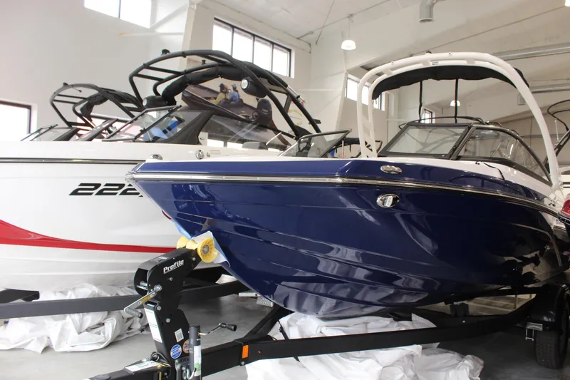 The Image of 2026 Yamaha Boats 195S in showroom, sleek blue design, alongside another boat model. - 0