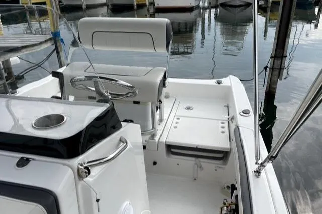 Slide: The Image of 2016 Yamaha Boats 190 FSH Deluxe interior, featuring helm and seating, docked at marina. - 5