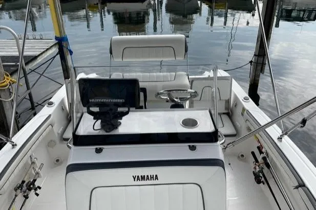 Slide: The Image of 2016 Yamaha Boats 190 FSH Deluxe interior with steering console and seating, docked by the water. - 6