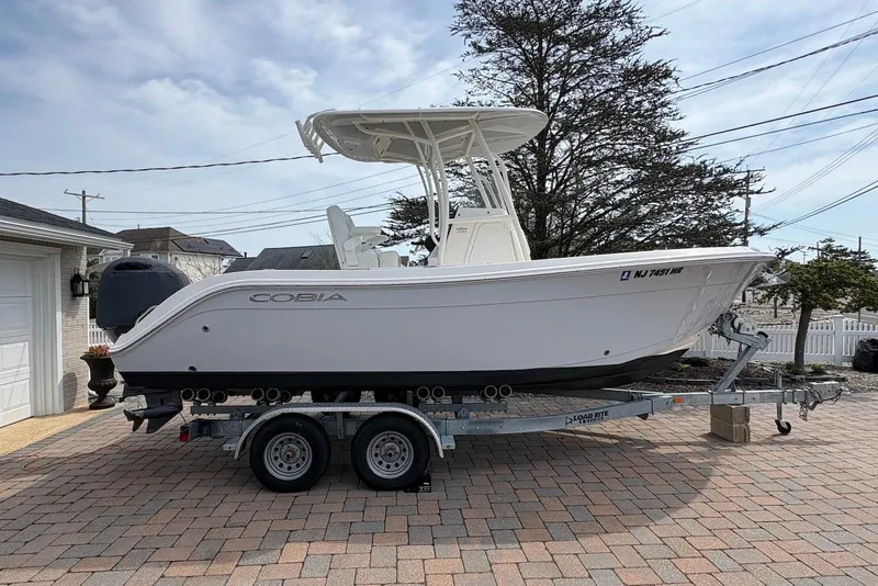 The Image of 2022 Cobia 220 Center Console boat on trailer in driveway. - 0