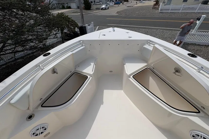 Slide: The Image of 2022 Cobia 220 Center Console boat with open storage compartments, docked near a residential area. - 16
