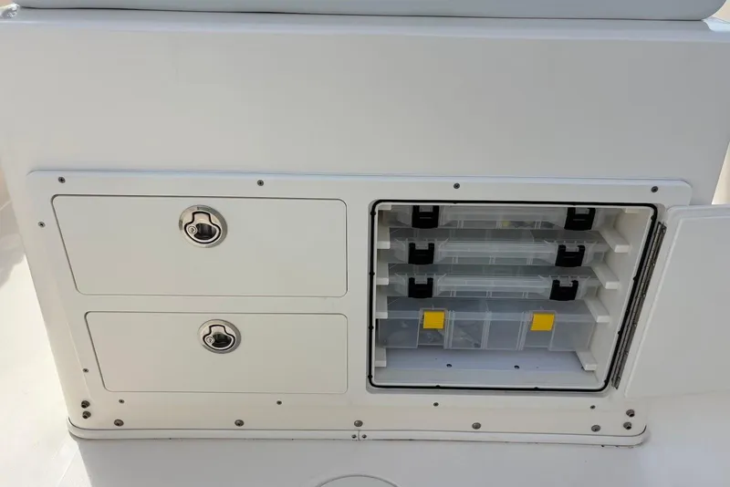 Slide: The Image of Storage compartments on a 2022 Cobia 220 Center Console boat, featuring organized tackle boxes. - 18