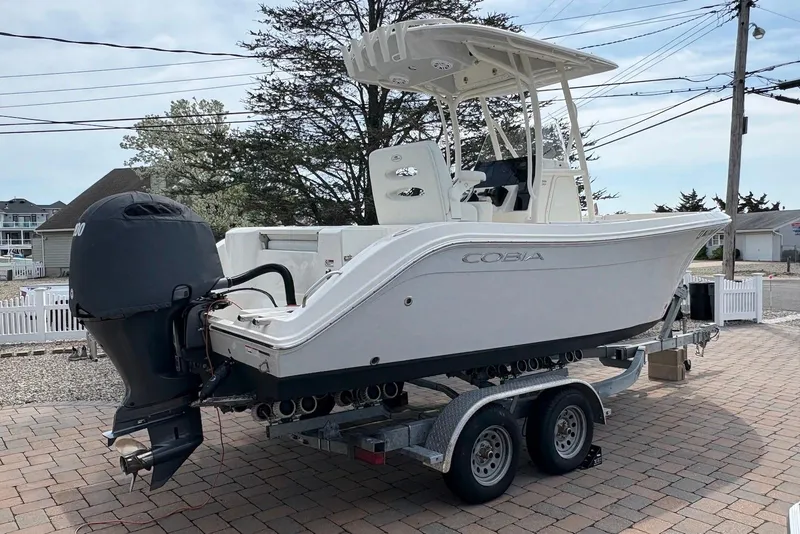 Slide: The Image of 2022 Cobia 220 Center Console boat on trailer, parked outdoors. - 2