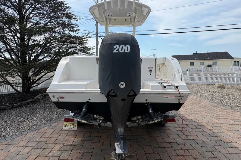 Slide: The Image of 2022 Cobia 220 Center Console boat with 200 HP engine on a paved driveway. - 3