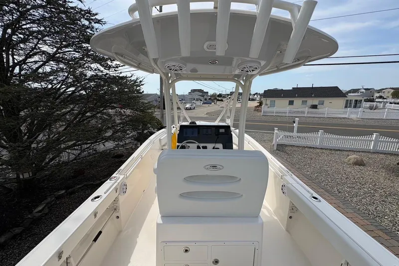 Slide: The Image of 2022 Cobia 220 Center Console boat with T-top, parked near residential area. - 6