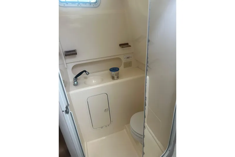 Slide: The Image of Compact bathroom in 2000 Shamrock 290 Walkaround boat, featuring sink and toilet. - 19