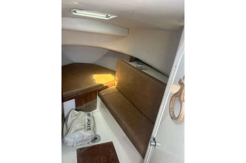 Slide: The Image of 2000 Shamrock 290 Walkaround cabin interior with brown seating and life jacket storage. - 20