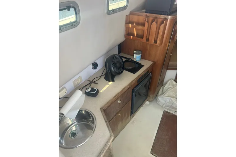 Slide: The Image of Compact kitchen area in a 2000 Shamrock 290 Walkaround boat with sink and fan. - 21