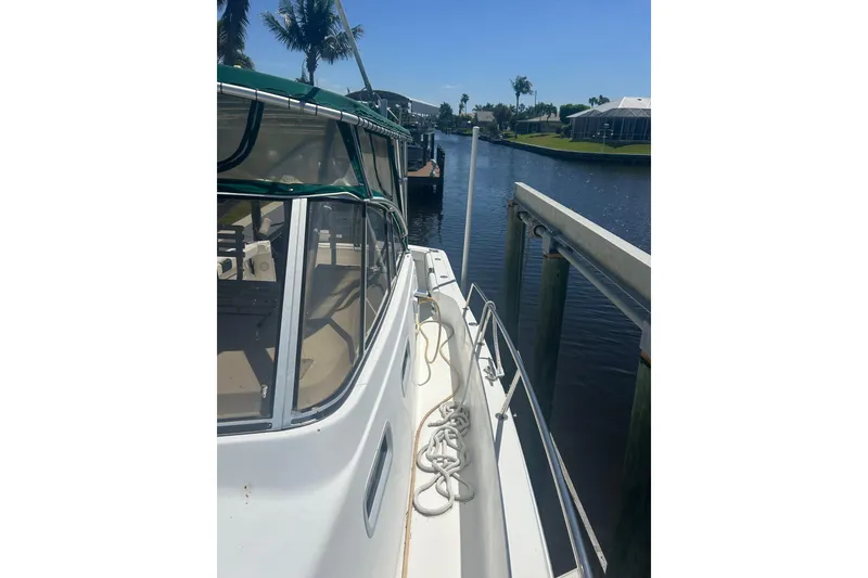 Slide: The Image of 2000 Shamrock 290 Walkaround boat docked by a canal on a sunny day. - 29