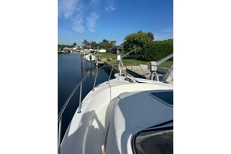 Slide: The Image of 2000 Shamrock 290 Walkaround boat docked by a scenic canal under a clear blue sky. - 4