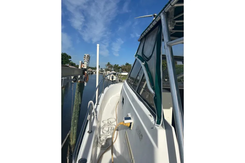 Slide: The Image of 2000 Shamrock 290 Walkaround boat docked, featuring green canopy and clear skies. - 6