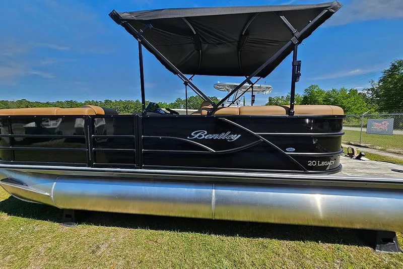 Slide: The Image of 2026 Bentley Pontoons Legacy 200 Navigator, sleek black design, parked on grass under blue sky. - 6