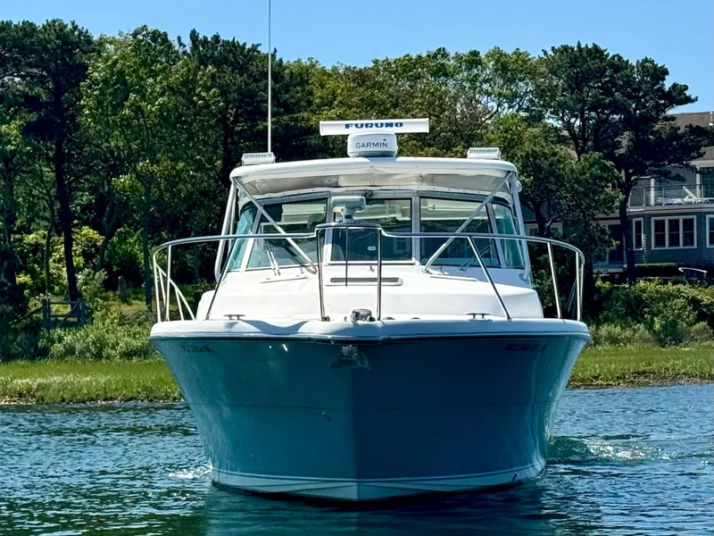 Slide: The Image of 2003 Pursuit 3400 Express boat on water, surrounded by lush greenery. - 6