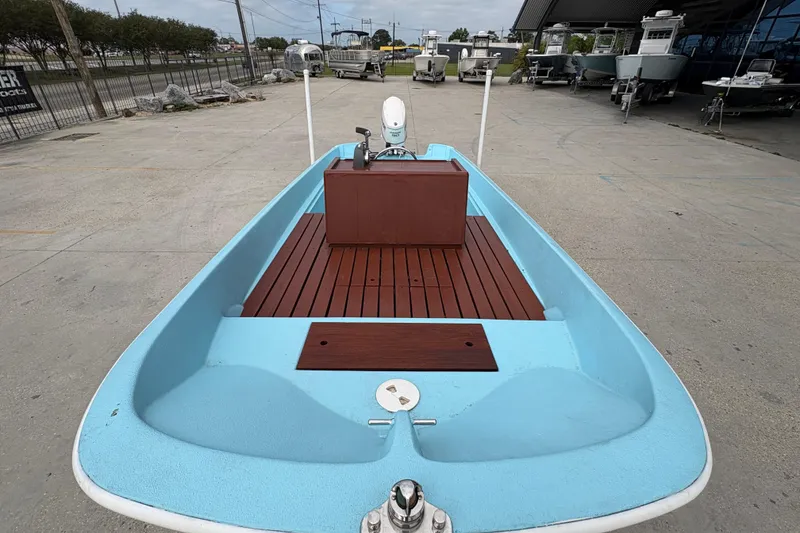Slide: The Image of 1963 Boston Whaler 16 boat with blue interior and wooden deck, displayed outdoors. - 10