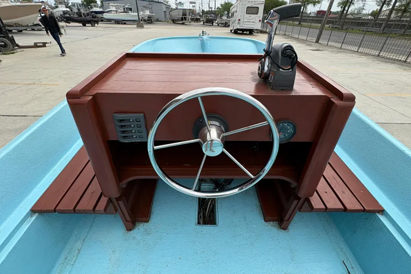 Slide: The Image of 1963 Boston Whaler 16 boat dashboard with steering wheel and controls, docked outdoors. - 12