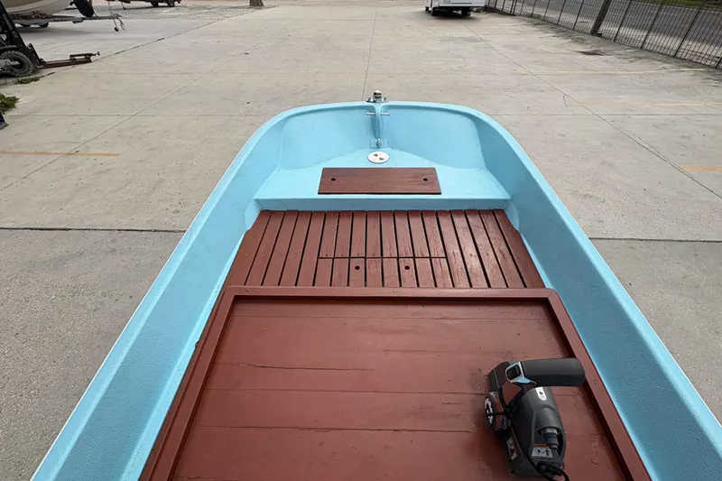 Slide: The Image of 1963 Boston Whaler 16 boat with blue hull and wooden deck, parked on concrete. - 13