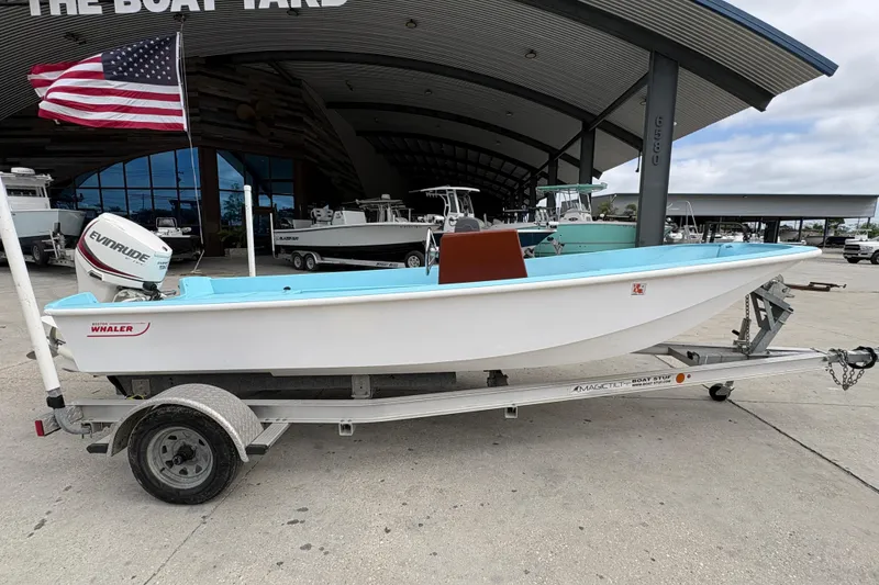 Slide: The Image of 1963 Boston Whaler 16 boat on trailer, displayed at a boat yard with American flag. - 2