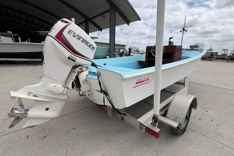 Slide: The Image of 1963 Boston Whaler 16 boat with Evinrude motor on trailer, outdoor setting. - 3