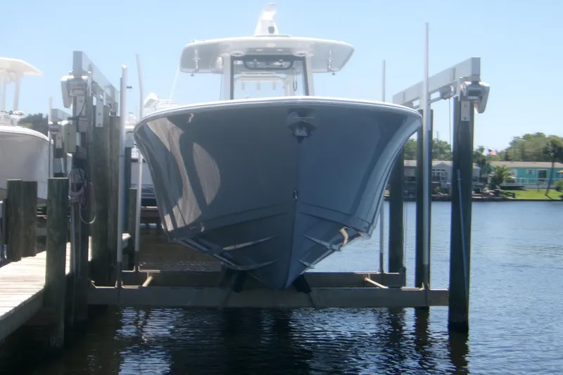 Slide: The Image of 2022 Sportsman Open 322 Center Console boat on lift by the water. - 23