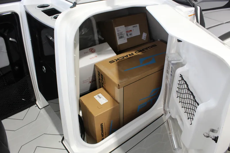 Slide: The Image of Storage compartment of 2026 Yamaha Boats 255XE filled with boxes and packages. - 10