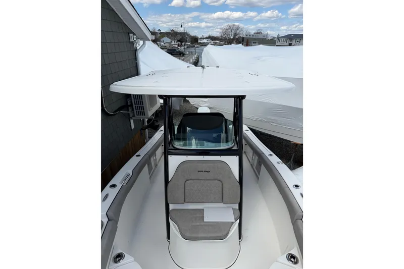 Slide: The Image of 2022 Seapro 239 DLX boat with T-top and seating, docked outdoors under cloudy sky. - 5