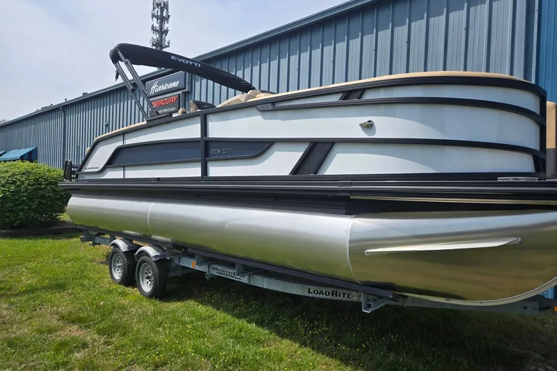 The Image of 2026 Evotti 523QL pontoon boat on trailer near industrial building. - 0