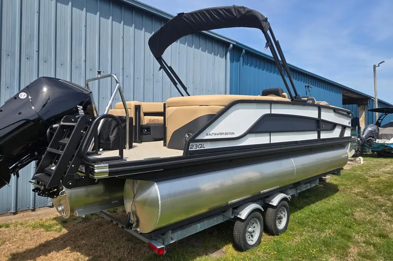 Slide: The Image of 2026 Evotti 523QL pontoon boat on trailer, parked near blue building. - 4