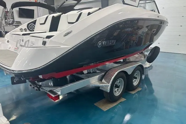 Slide: The Image of 2025 Yamaha Boats 222SE on trailer in showroom, sleek design, dual axle. - 9