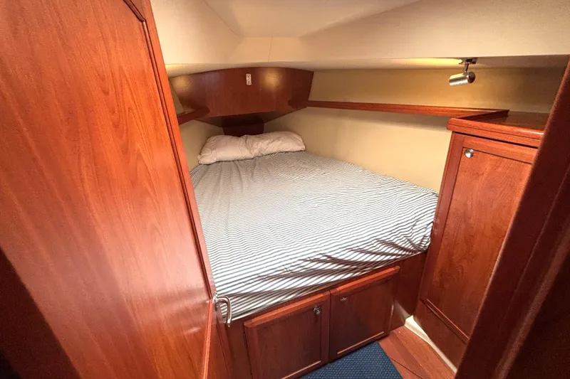 Slide: The Image of Cozy cabin interior of 2011 Hunter 39 sailboat with wooden furnishings and striped bedding. - 18